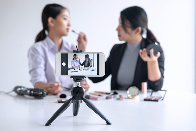 Twee mooie vrouwen Blogger, online op sociale media, toont het huidige leerprogramma voor cosmetische producten en zendt live streaming video uit naar het sociale netwerk terwijl ze online lesgeven