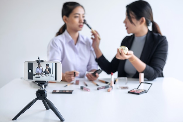 Twee mooie vrouwen Blogger, online op sociale media, toont het huidige leerprogramma voor cosmetische producten en zendt live streaming video uit naar het sociale netwerk terwijl ze online lesgeven