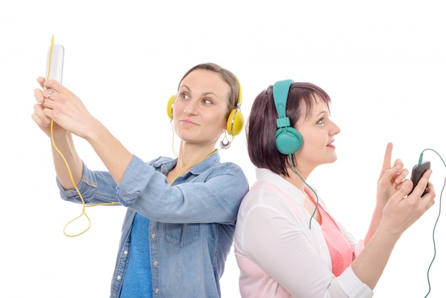 Twee mooie vrouwen die aan muziek met telefoon luisteren