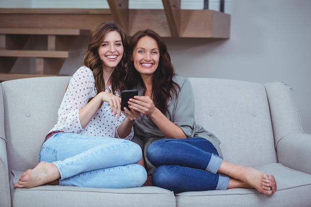 Twee mooie vrouwen kijken naar de mobiele telefoon