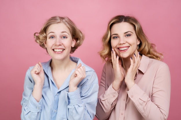 Foto twee mooie vrouwen knijpen vrolijk en enthousiast in hun vuisten om zich zorgen te maken over hun favoriete team.