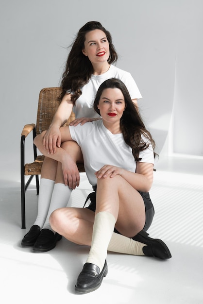 Twee mooie vrouwen tweelingzusjes poseren op een witte achtergrond
