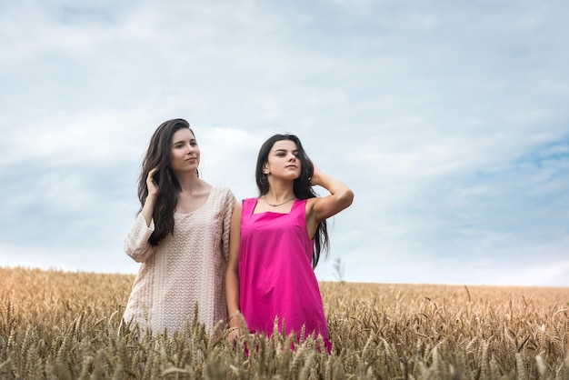 Twee mooie zussen genieten van vrijheid in het tarweveld, zomerdag