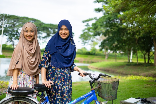 Twee moslimvrouwen fietsen in de tuin