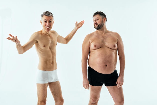 Twee multi-etnische mannen poseren voor een body positive beautyset voor mannen. Shirtless jongens met verschillende leeftijden en lichaam met boxer-ondergoed