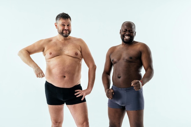 Twee multi-etnische mannen poseren voor een body positive beautyset voor mannen. Shirtless jongens met verschillende leeftijden en lichaam met boxer-ondergoed