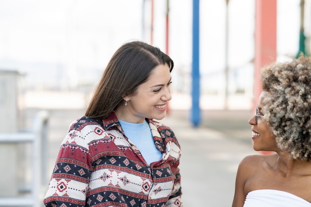 Twee multi-etnische vrouwen die een stel zijn, kijken elkaar aan en lachen