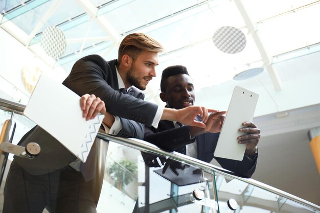 Twee multinationale jonge zakenlieden die zaken bespreken tijdens vergadering in bureau.