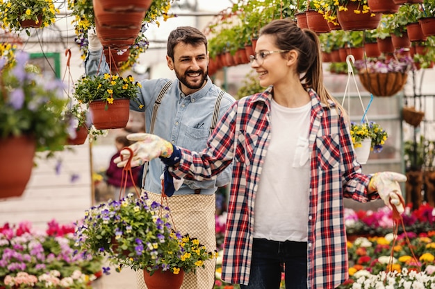 Twee ondernemers houden potten met bloemen vast en vertellen het. Kwekerij interieur.