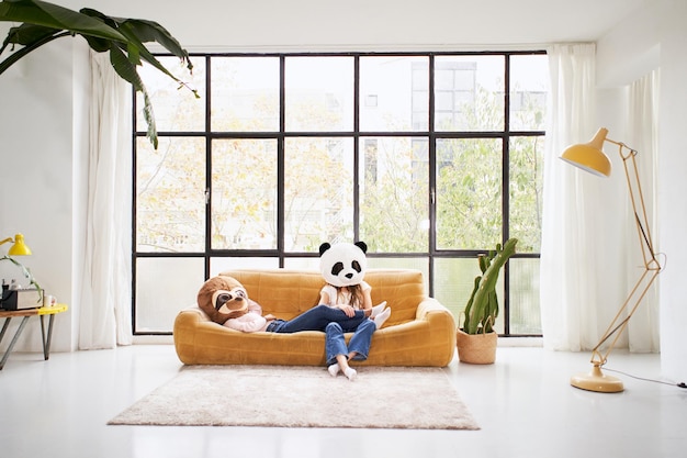 Twee onherkenbare vrouwen met dierenmasker dragen panda liggend op de bank thuis mooie woonkamer indoo