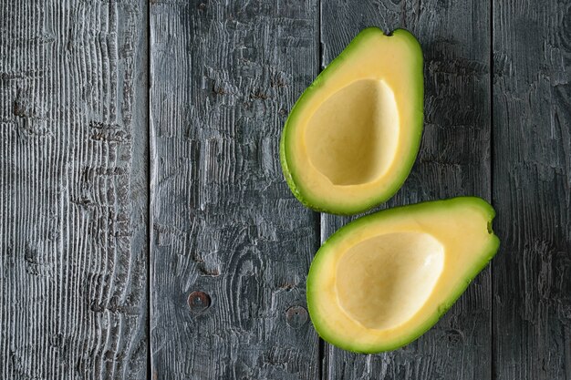 Twee ontpit avocado helften op een zwarte houten tafel