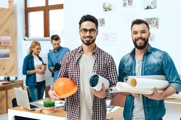 Twee ontwerpersarchitecten die met blauwdrukken stellen.