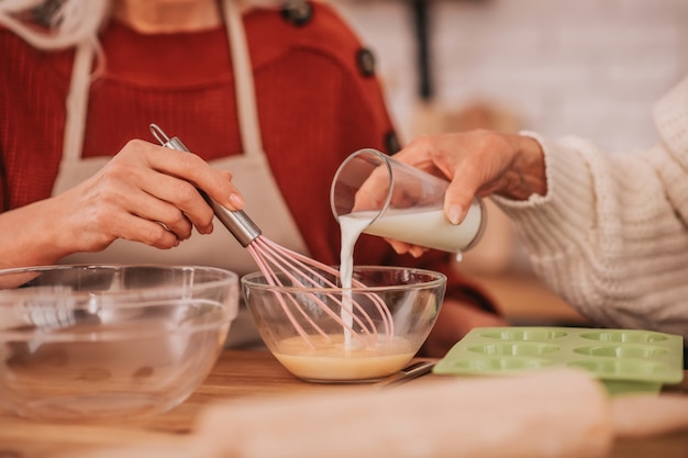 Twee oudere vrouwen die melk in de keuken kloppen