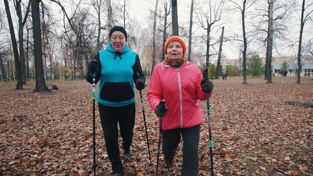 Twee oudere vrouwen lopen op stokken van nordic walking op een late herfst