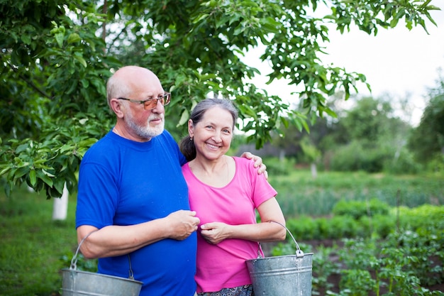 Twee ouderen in moestuin met emmers