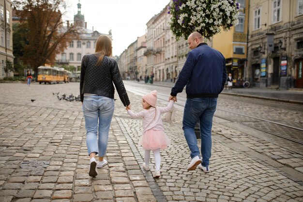 Twee ouders met een dochtertje lopen door de straten van de oude stad.