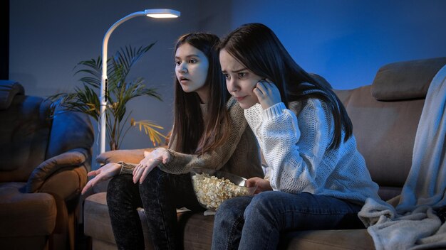 Foto twee overstuur en geïrriteerde meisjes die 's avonds naar een voetbalwedstrijd op tv kijken