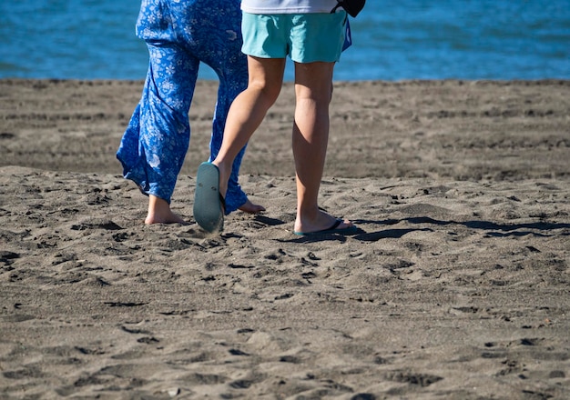 Twee paar verliefde benen lopen op het zand van een strand aan zee