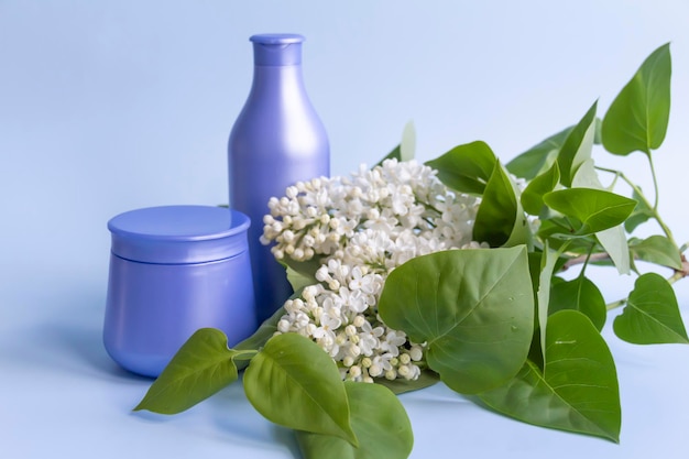 Twee paarse potten met cosmetische producten en crèmes met fris bloeiende en geurige lila bloemen