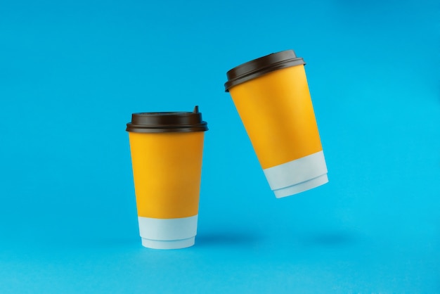 Foto twee papieren koffiekopjes op een blauwe achtergrond