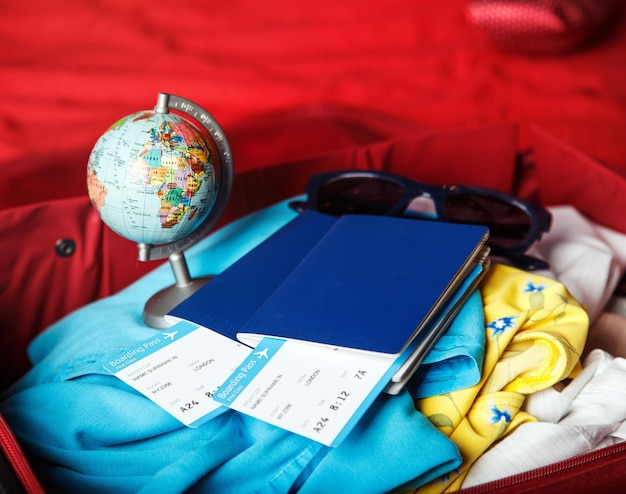 Twee paspoorten met vliegtickets op reiskoffer met kleine wereldbol