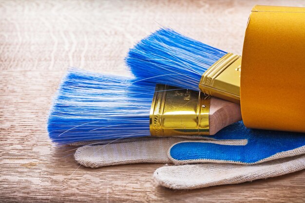 Twee penselen in de rol van duct tape en werkhandschoenen op een houten bord