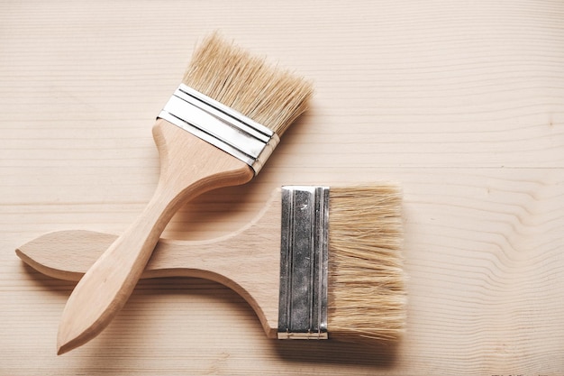 Twee penselen met een houten handvat en natuurlijke haren op een houten ondergrond