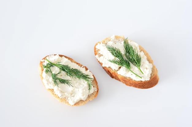 twee plakjes brood met dille bovenop en zachte kaas bovenop