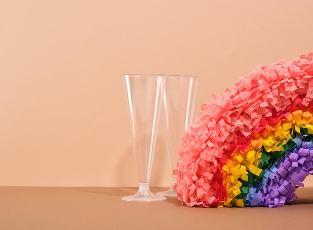 Twee plastic drinkglazen en een kleurrijke regenboogpinata Kopieer ruimte voor tekst Verjaardagsfeestje en prettige vakantie