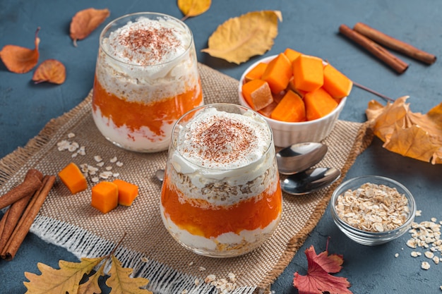 Twee porties pompoendessert met room en cacao op een herfstachtergrond Zijaanzichtclose-up