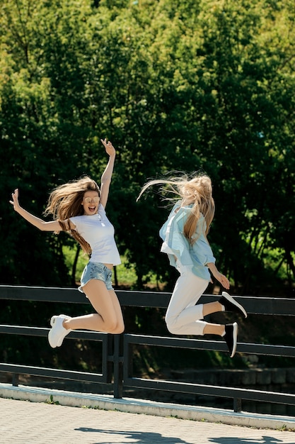 Twee positieve en gelukkige jonge vrouwen die samen springen