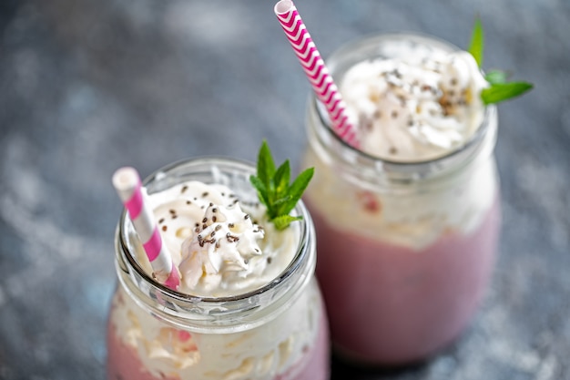 Twee potten milkshake of smoothie met veenbessen, aardbeien en bosbessen staan op stenen oppervlak