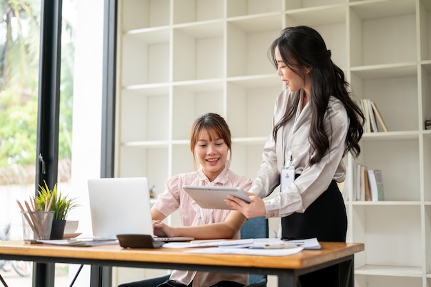 Twee professionele Aziatische zakenvrouwen bespreken werk om verkoopgegevens te analyseren