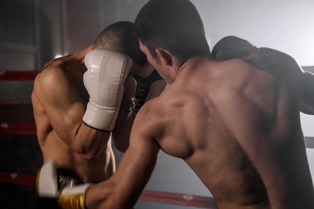 Twee professionele jonge, gespierde, shirtloze mannelijke boksers die vechten in een boksring fotografie van hoge kwaliteit