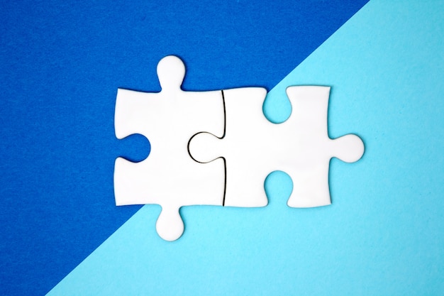 Twee puzzelstukjes verbinden elkaar op blauw geometriekleurpapier.