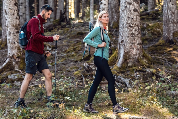 Twee reiswandelaars met rugzak wandelen terwijl ze het landschap in het bos bekijken.