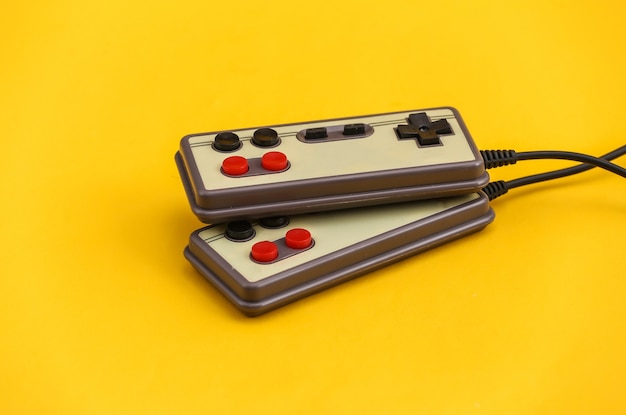 Twee retro gamepads op gele achtergrond. Gamen, videospelletjes.