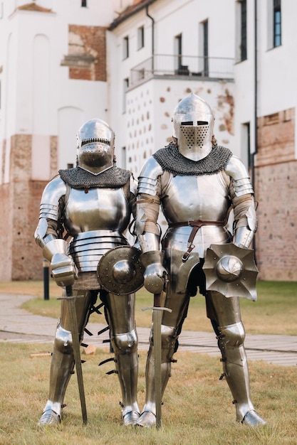Twee ridders in oude metalen harnassen staan bij de stenen muur van het kasteel