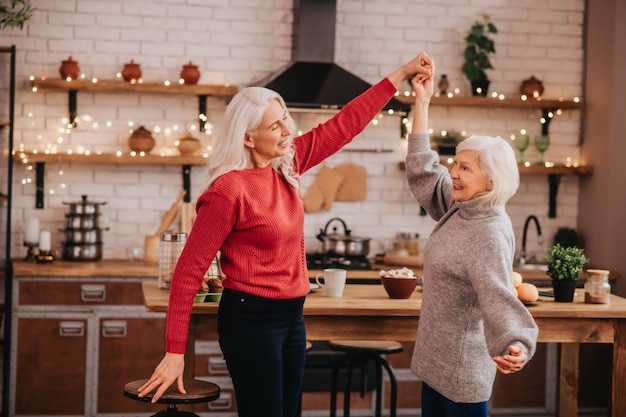 Twee rijpe grijsharige positieve dames die pret hebben