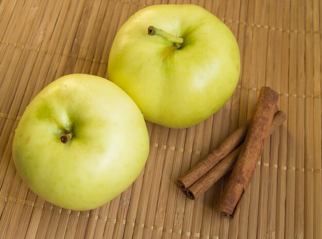 Twee rijpe groene appels en kaneelstokjes op bamboe servet