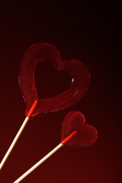 Twee rode doorzichtige hartvormige lolly's op een donkerrode achtergrond Love Banner voor Valentijnsdag