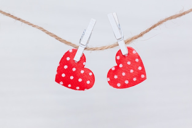 Twee rode harten die op een draad op witte houten achtergrond hangen. Valentijnsdag, liefde, bruiloft concept. Plat lag, bovenaanzicht.