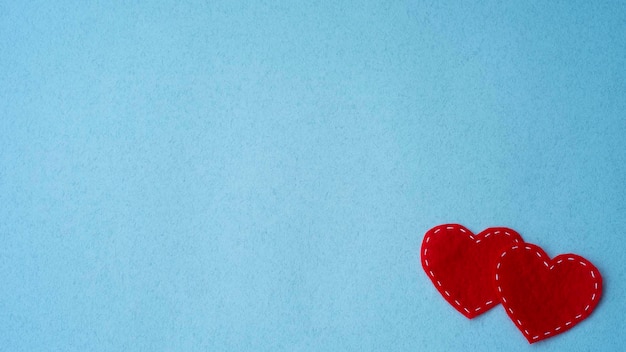 Twee rode harten van vilt op een blauwe achtergrond Liefdessymbool