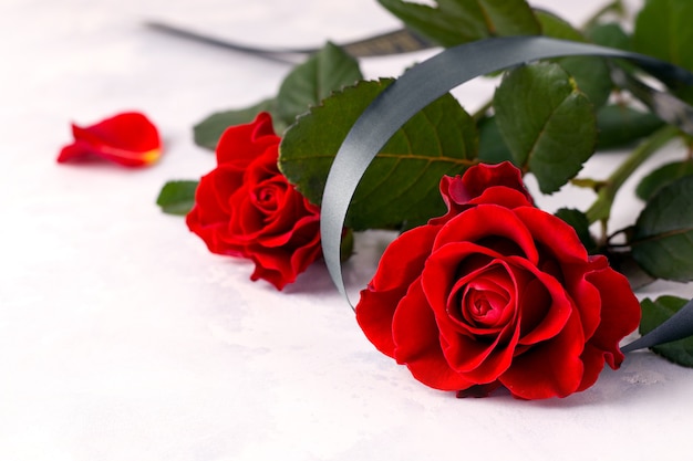 Twee rode rozen met een zwart lint op wit