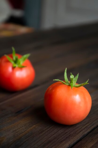 Twee rode tomaten liggen op een houten tafel. Tomatenvruchten liggen op tafel