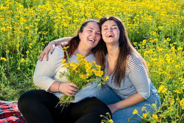 Twee ronde meisjes in een veld met madeliefjes lachen. onbezorgd moment in de open lucht na heropening