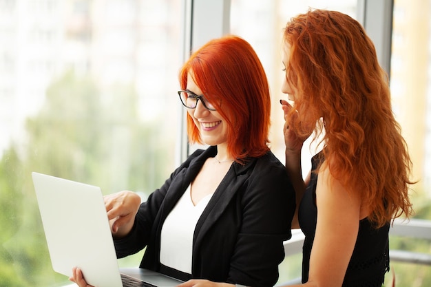 Twee roodharige vrouwen werken samen in het moderne kantoor