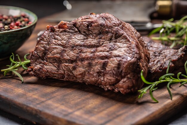 Twee rundvlees rumpsteaks met kruiden tomaten zout en specerijen op slager bord.