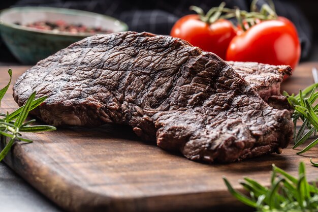 Twee rundvlees rumpsteaks met kruiden tomaten zout en specerijen op slager bord.