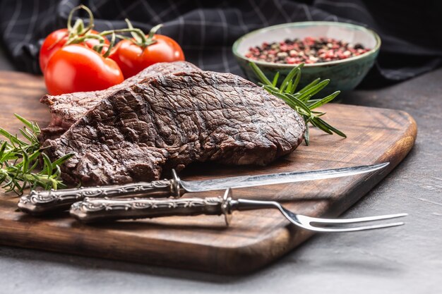 Twee rundvlees rumpsteaks met kruiden tomaten zout en specerijen op slager bord.